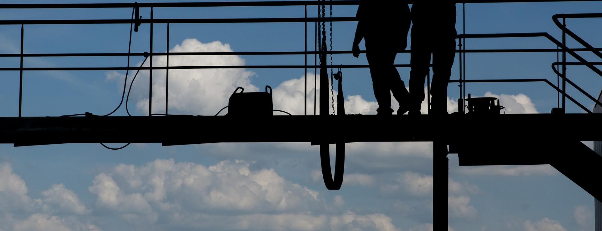 men in hardhats on scaffolding with blue sky in background