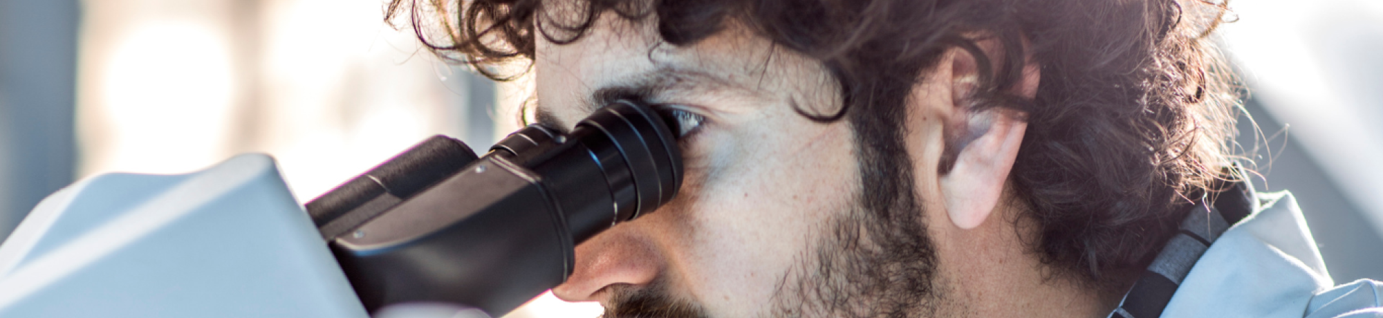 Male researcher looking through a microscope